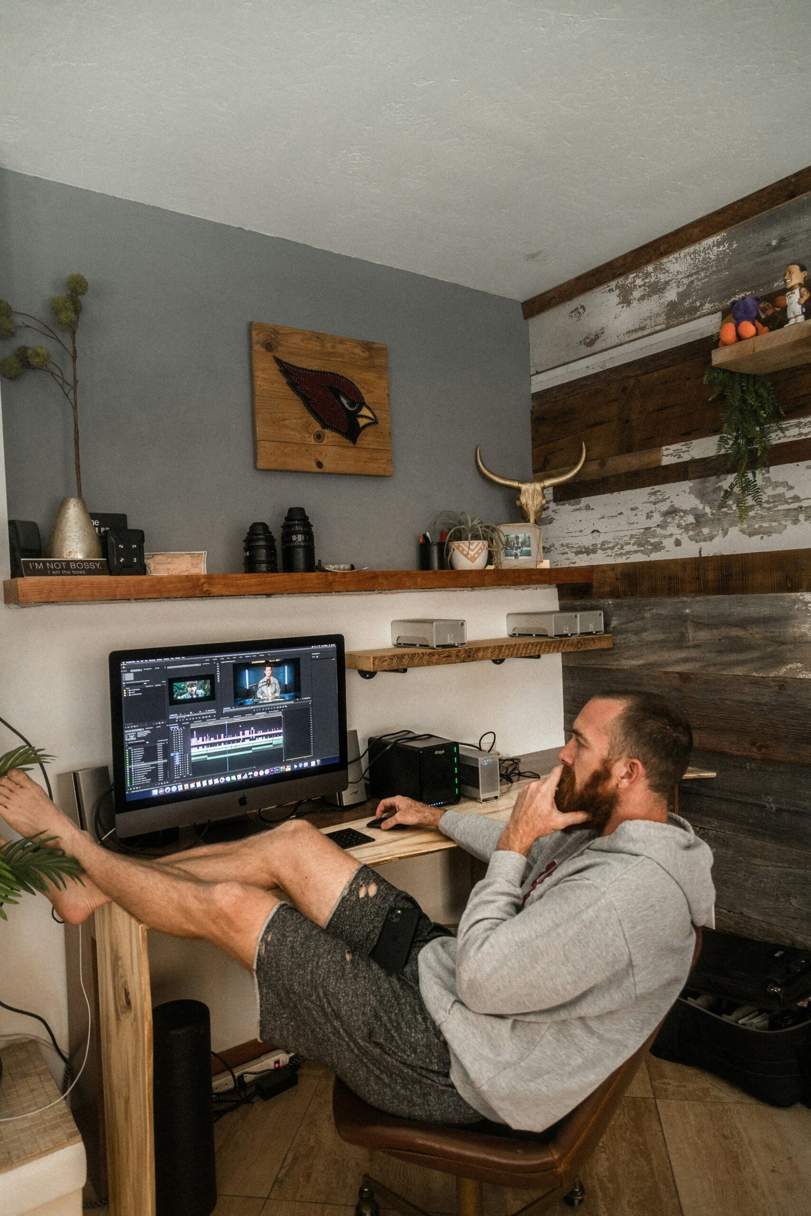 man in gray shirt and black shorts sitting on chair using laptop computer